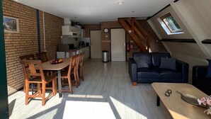 A compact living space with a kitchen, dining area, and a loft bedroom with a skylight.