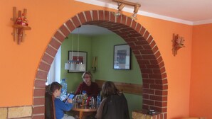 Un coin repas agrémenté d’une arche en briques, d’une table avec des chaises et d’un mur vert orné de tableaux encadrés.
