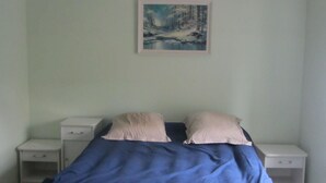 Une chambre à coucher avec un lit, deux tables de chevet et un tableau accroché au mur.