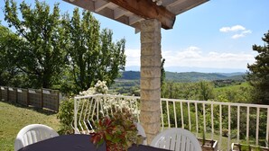A covered outdoor area with a table and chairs, a stone pillar, and a view of a green landscape. - Relaxing Retreat in Bathernay (Bathernay)