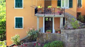 A two-story house with a balcony, potted plants, and a stone wall. - Holiday Home in Rio Near Fishing Villages (Sesta Godano)
