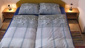 A bed with a floral-patterned bedspread and pillows, flanked by two bedside tables with lamps. - Modern Apartment in Carlsbad With Garden (Karlovy Vary)