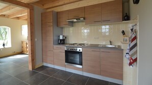 Eine moderne Küche mit Holzschränken, einem Edelstahlherd und einer gefliesten Spritzschutzwand.
