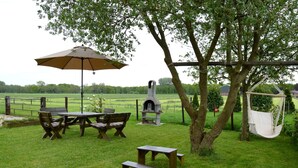 Eine Terrasse im Freien mit Tisch und Stühlen, einer Hängematte und einem Steinofen.
