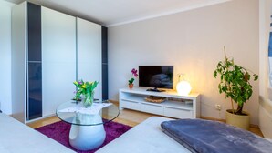 A modern living room with a sofa, a glass coffee table, a flat-screen TV, a lamp, and a potted plant. - Simplistic Apartment in Piesendorf - Walchen near Ski Slopes (Piesendorf)