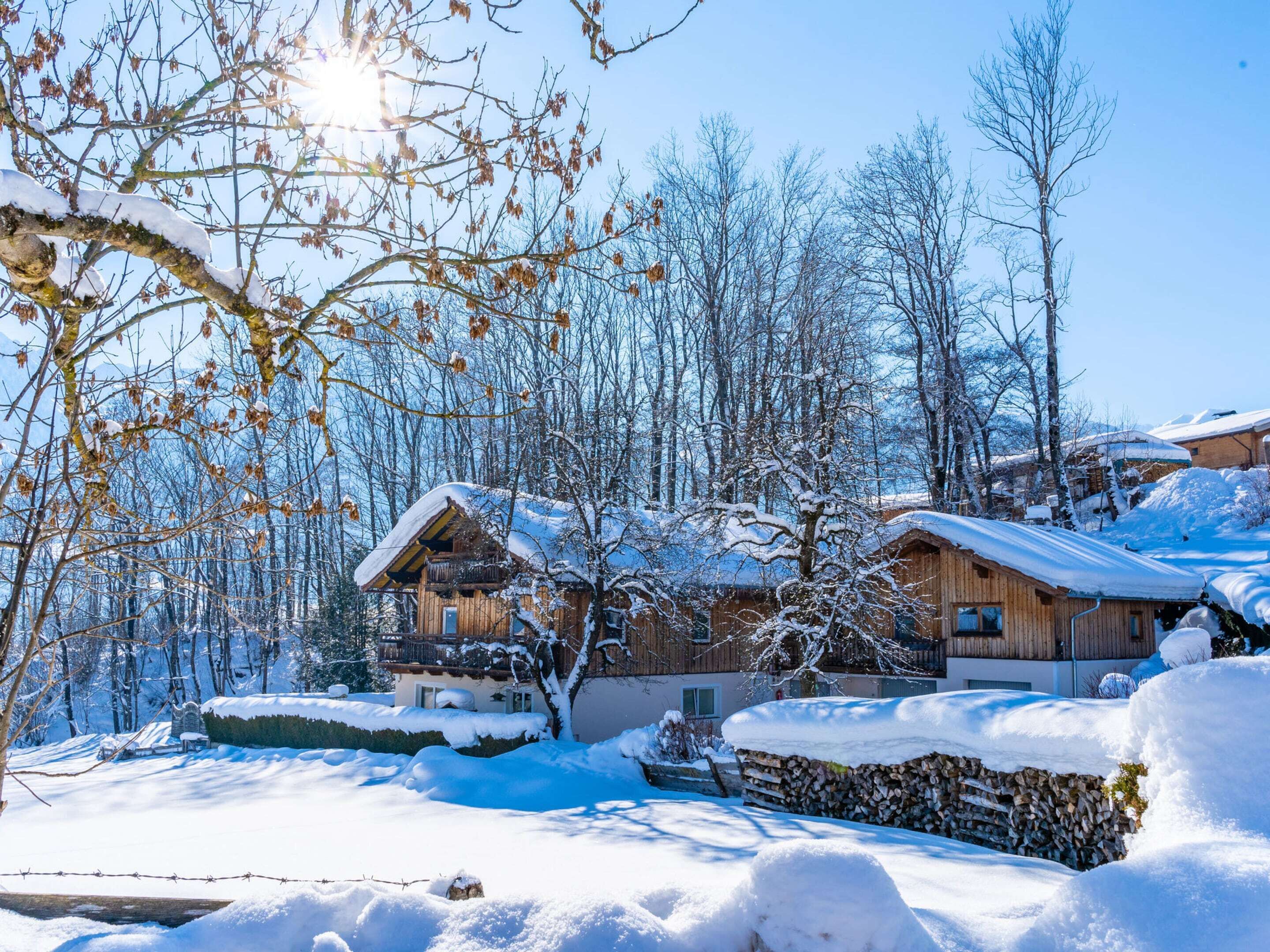 Un pueblo cubierto de nieve con casas de madera, una cerca de madera y un cielo azul despejado.