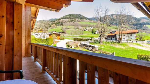A wooden balcony with a view of a rural landscape, including houses and mountains. - Simplistic Apartment in Piesendorf - Walchen near Ski Slopes (Piesendorf)