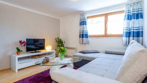 A modern living room with a sofa, TV, and decorative plants. - Simplistic Apartment in Piesendorf - Walchen near Ski Slopes (Piesendorf)