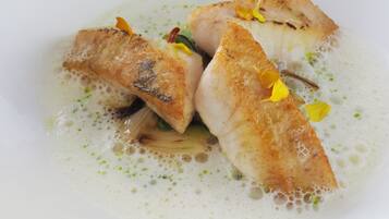 Un plato de pescado y verduras en salsa cremosa.