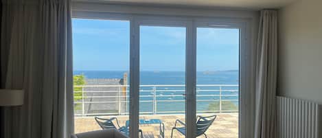 Et værelse med en stor skydedør, der fører ud til en balkon med udsigt over havet og både.