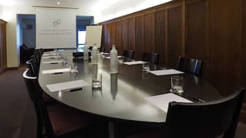 Un salón de conferencias con una mesa larga, sillas y un cartel en el fondo.