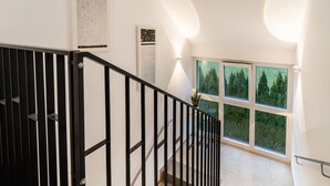Eine moderne Treppe mit schwarzen Geländern und Blick auf eine grüne Landschaft durch große Fenster.