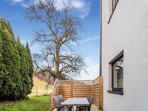 A patio with a table and chairs, a wooden fence, and a tree. - Apartment in St. Georgen / Salzburg Near ski Area (Bruck an der Grossglocknerstrasse)