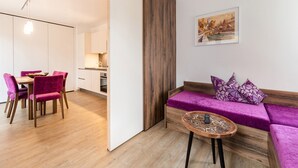 Ein modernes Wohnzimmer mit einem violetten Sofa, einem Holztisch und einem Essbereich mit Holztisch und Stühlen.