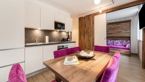 Eine moderne Küche mit weißen Schränken, einem Holztisch und violetten Stühlen.