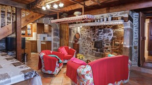 Un interior rústico con pared de piedra, muebles de madera y suelo de baldosas.