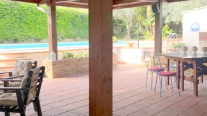 A covered patio area with a pool view, outdoor seating, and a barbecue grill. - Belvilla by OYO Holiday Home in Caltagirone (Caltagirone)