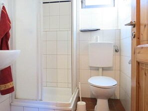 A small bathroom with a toilet, a shower, and a sink. - Wohnung mit Terrasse in Huddingen (Bad Wildungen)