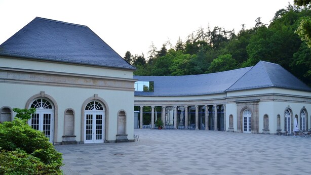 Un patio amplio con un edificio de estilo clásico, ventanas de arco y suelo de baldosas.