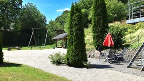 Un parque con un columpio, un pabellón y una sombrilla roja.