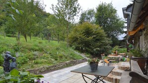 A patio with a stone table and chairs, surrounded by potted plants and a statue. - Cozy Apartment in Immerath near Fishing (Immerath)