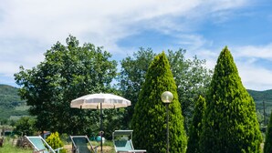A swimming pool with lounge chairs and an umbrella, surrounded by trees and hills. - Beautiful Farmhouse With Pool (San Marcello Piteglio)