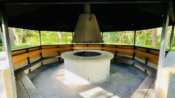 Un área de estar al aire libre cubierta con bancos y una chimenea central.