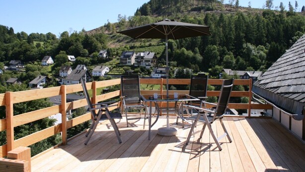 A wooden deck with outdoor furniture, a table, and an umbrella. - Apartment Near Willingen With Terrace (Willingen)