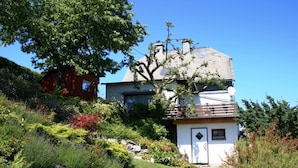 A two-story house with a sloped roof, surrounded by a well-maintained garden with various plants and a lawn. - Apartment Near Willingen With Terrace (Willingen)