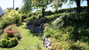 A landscaped garden with a variety of plants and a stone wall. - Apartment Near Willingen With Terrace (Willingen)
