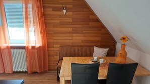 A dining area with a wooden table and chairs, a radiator, and a wall-mounted clock. - Apartment Near Willingen With Terrace (Willingen)