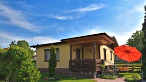 A yellow building with a covered porch and a red umbrella. - Cozy Holiday Home in Großbreitenbach near Schwarza Valley (Grossbreitenbach)