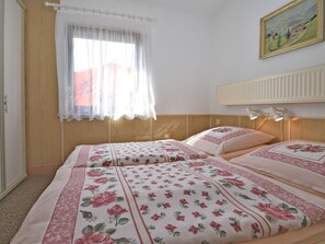 A bedroom with two beds, floral bedding, a window with sheer curtains, and a painting on the wall. - Cozy Holiday Home in Großbreitenbach near Schwarza Valley (Grossbreitenbach)