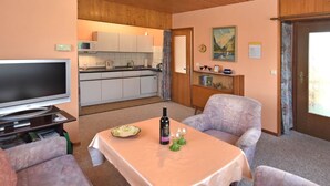 A living room with a television, a table with a bottle and glasses, and two patterned armchairs. - Cozy Holiday Home in Großbreitenbach near Schwarza Valley (Grossbreitenbach)