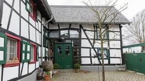 A traditional half-timbered building with a green door and windows, a cobblestone courtyard, and potted plants. - Apartment in Schleiden (Schleiden)