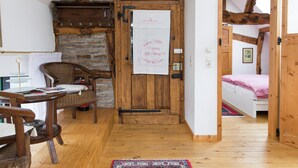 A cozy room with a wooden door, a bed with a checkered blanket, a wicker chair, and a small table with a lamp. - Apartment in Schleiden (Schleiden)