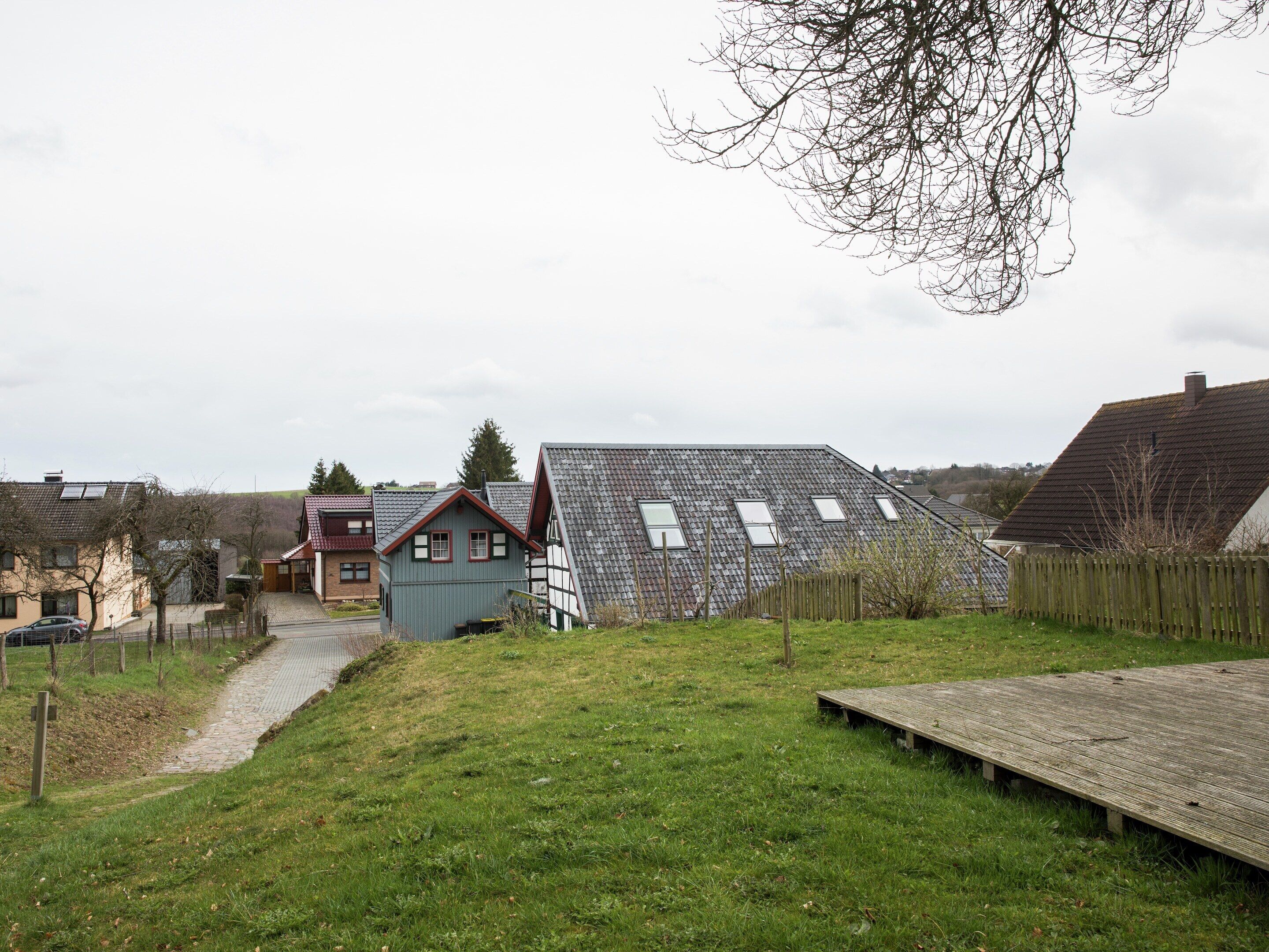 A residential area with houses, a grassy yard, and a wooden deck.