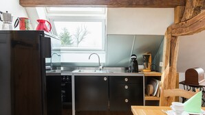 A compact kitchen with a sink, stove, and wooden beams above. - Apartment in Schleiden (Schleiden)