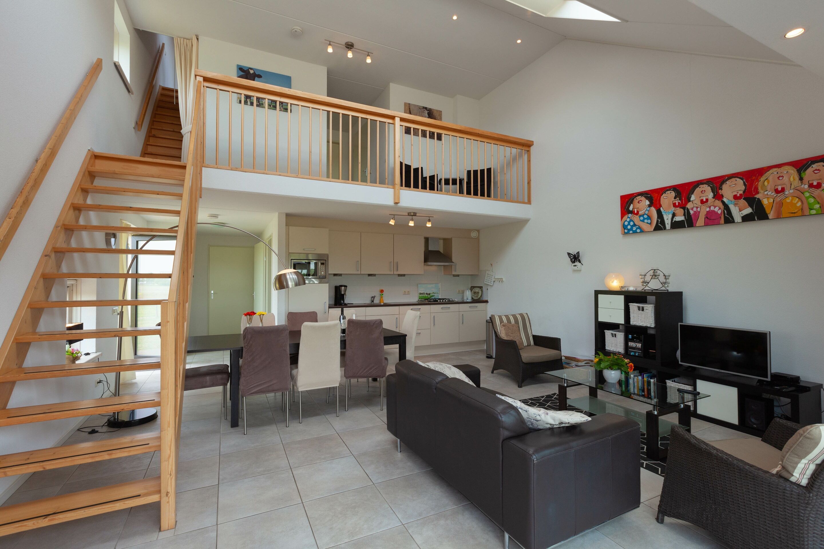 A spacious living area with a staircase, dining table, sofas, and a TV.
