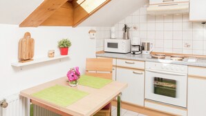 Une cuisine compacte avec des meubles blancs, un four à micro-ondes, une machine à café et une cuisinière.