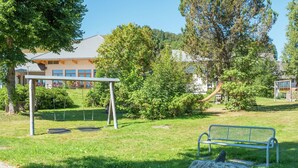 Un parc avec une balançoire, un banc et un grand rocher.