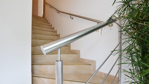 Eine Treppe mit beigen Fliesen und Edelstahlhandläufen.