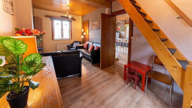 A wooden interior with a staircase, a sofa, a dining table, and a potted plant. - Pretty Holiday Home near Durbuy & La Roche-en-Ardennes (Erezee)