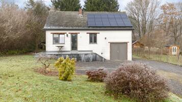 Simple, eco-friendly home with a sloped roof and solar panels, featuring a glass door entrance and a small porch.