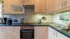A modern kitchen with wooden cabinets, a built-in oven, a microwave, and a kettle. - Pretty Holiday Home near Durbuy & La Roche-en-Ardennes (Erezee)