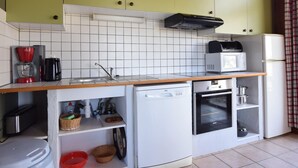 A compact kitchen with white appliances, a microwave, and a toaster. There are cabinets above the counter and a small oven below.