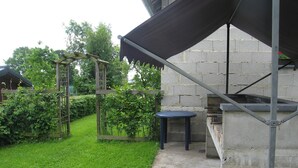 Un espace patio aménagé avec une table et des chaises, une pergola et un mur en briques.