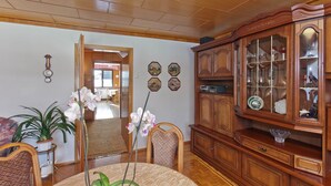 Un comedor con un aparador de madera, una mesa, sillas y una planta en maceta.