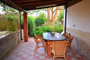 A covered patio with a checkered floor, wicker chairs, and a round table. - Detached House Near the sea With Garden and Terrace (Augusta)