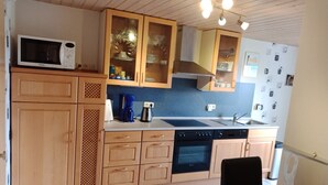 A kitchen with wooden cabinets, a microwave, a coffee maker, and a dishwasher. - Apartment in Leudersdorf, Eifel With Terrace (Üxheim)